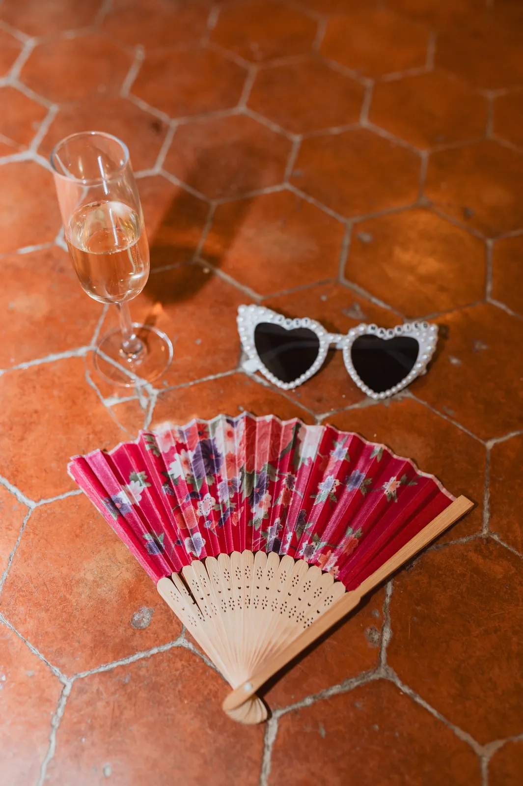 Coupe de champagne, éventail et lunettes en cœur sur les tomettes
