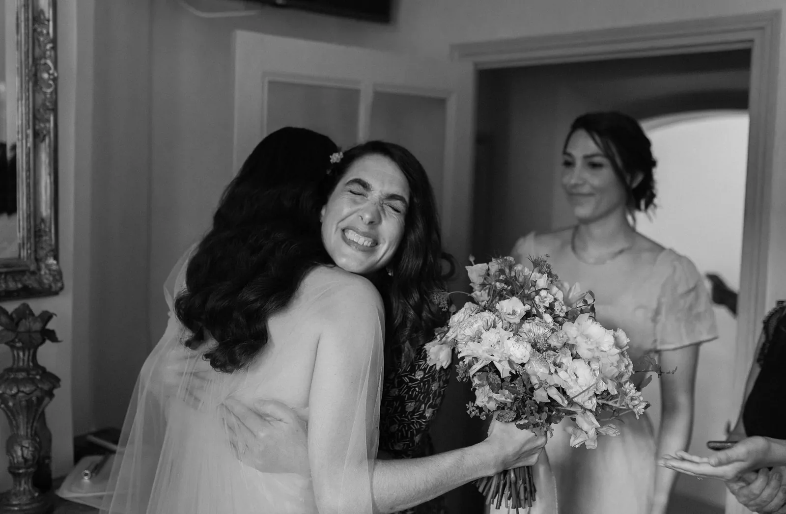 Une amie serre la mariée dans ses bras pendant les préparatifs